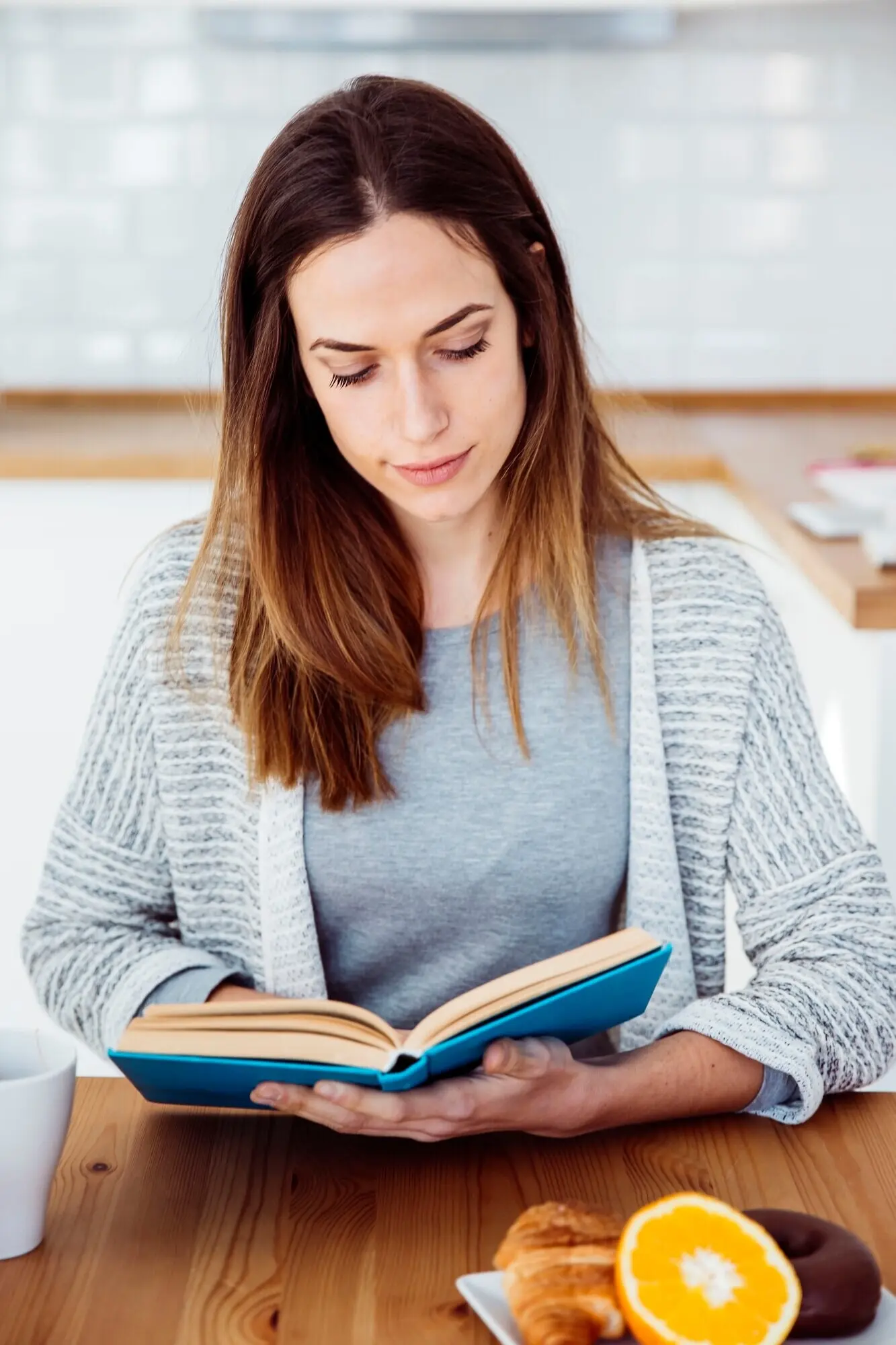 Beim Frühstück liest eine Frau