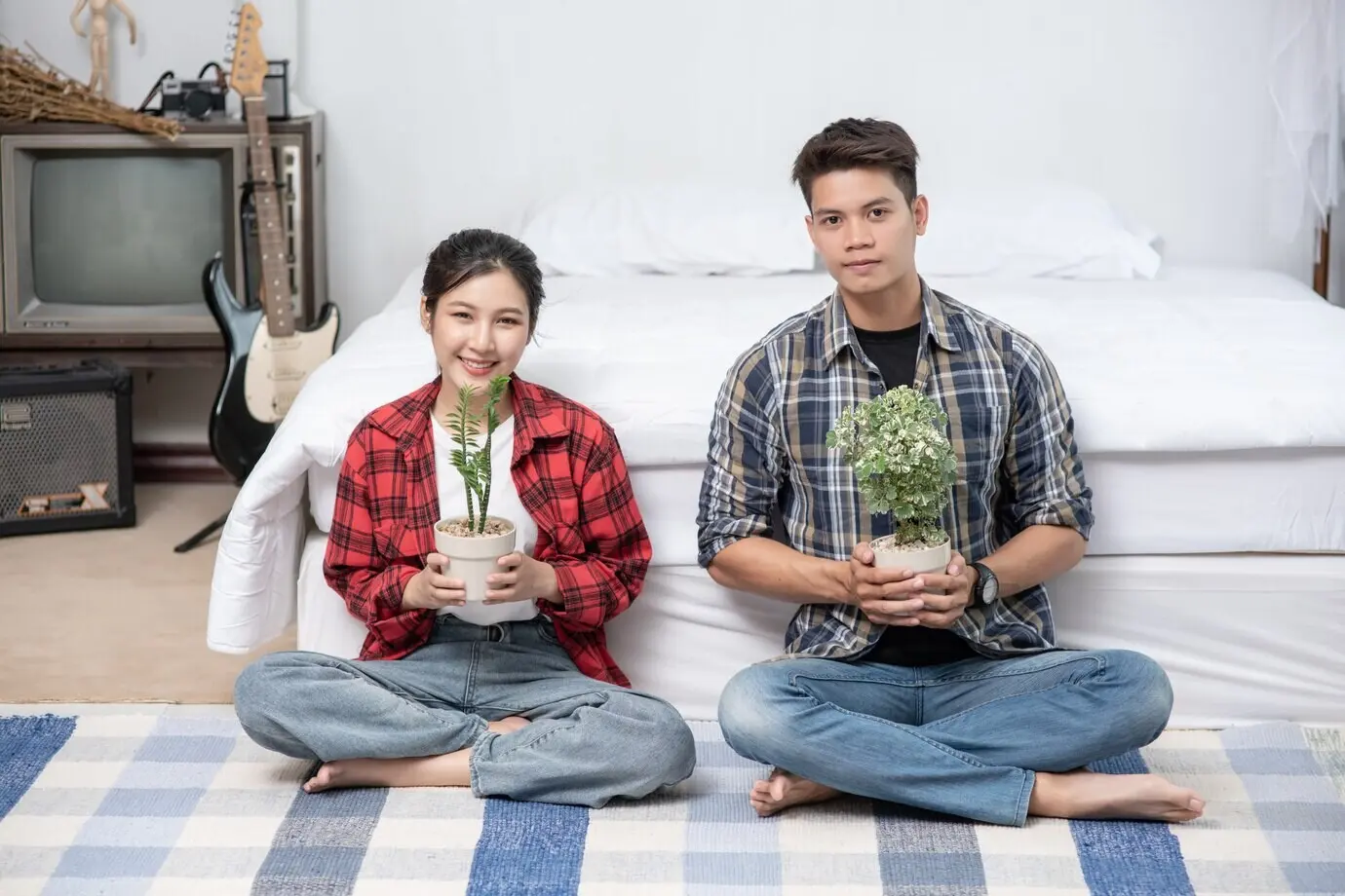 Männer und Frauen sitzen im Haus und halten Pflanzentöpfe.